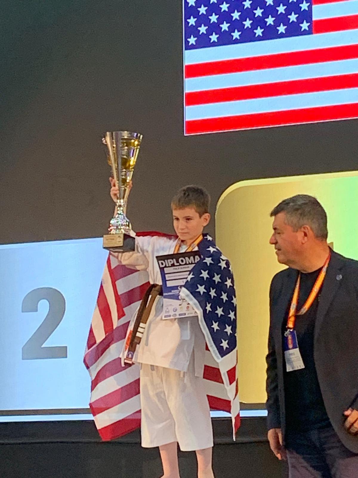 Rokah Karate student wrapped in the US flag with a championship trophy